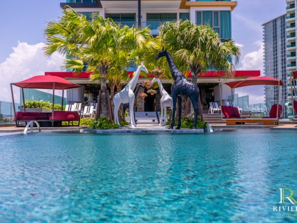 Poolside Riviera Group scene with three giraffe sculptures, palm trees, red shade canopies, and modern buildings in the background.