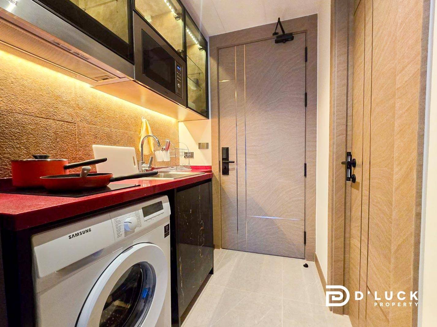 Riviera-Ocean-Drive-Studio-Rent-2609 10 Compact modern kitchenette with a red countertop, front-loading Samsung washing machine, black lower cabinets, and a wall-mounted microwave above the counter.