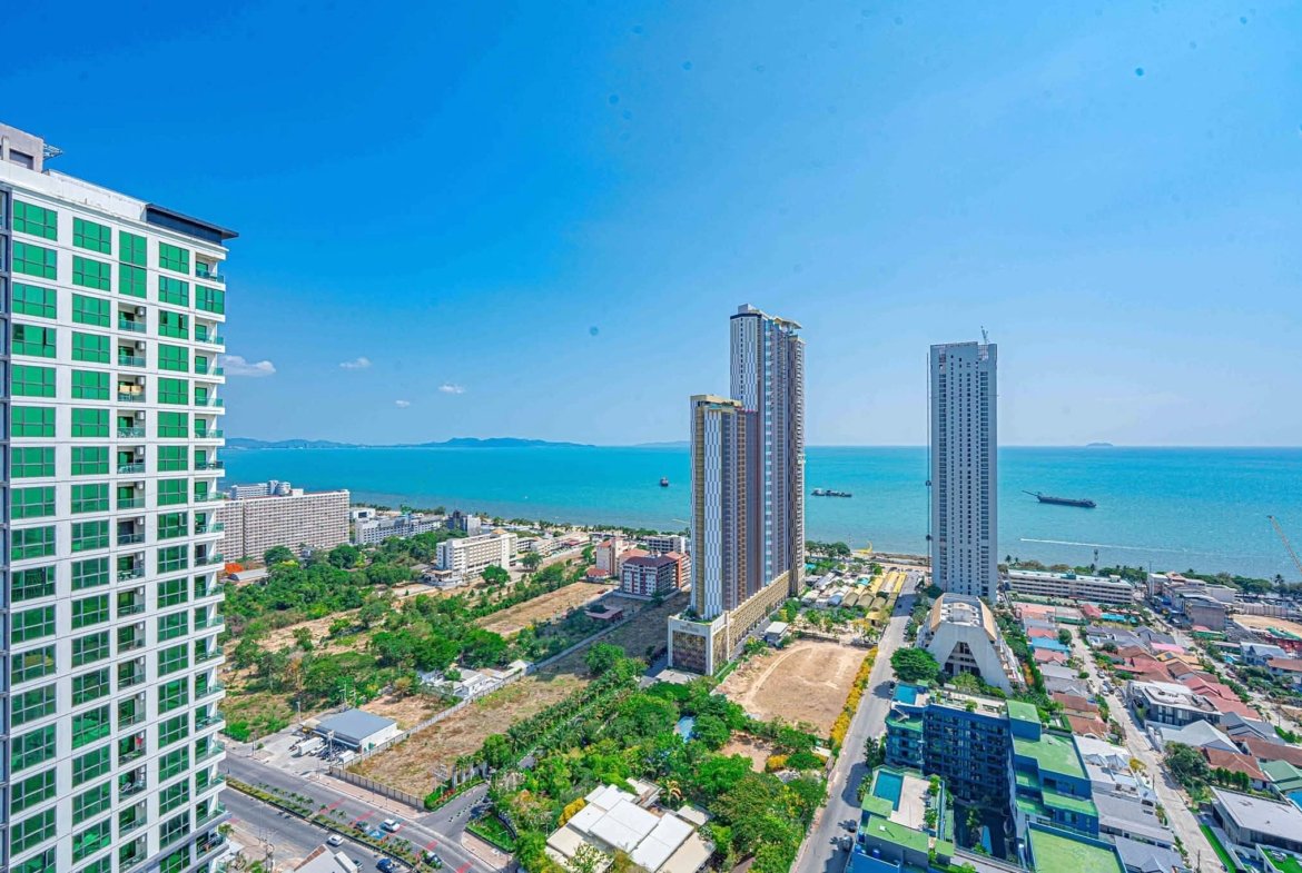 Aerial view of a coastal city with high-rise buildings along the shoreline and a blue ocean in the background, under a clear sky.
