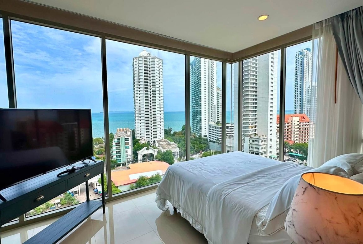 Hotel room with floor-to-ceiling windows overlooking the ocean and surrounding high-rise buildings at sea bluff.