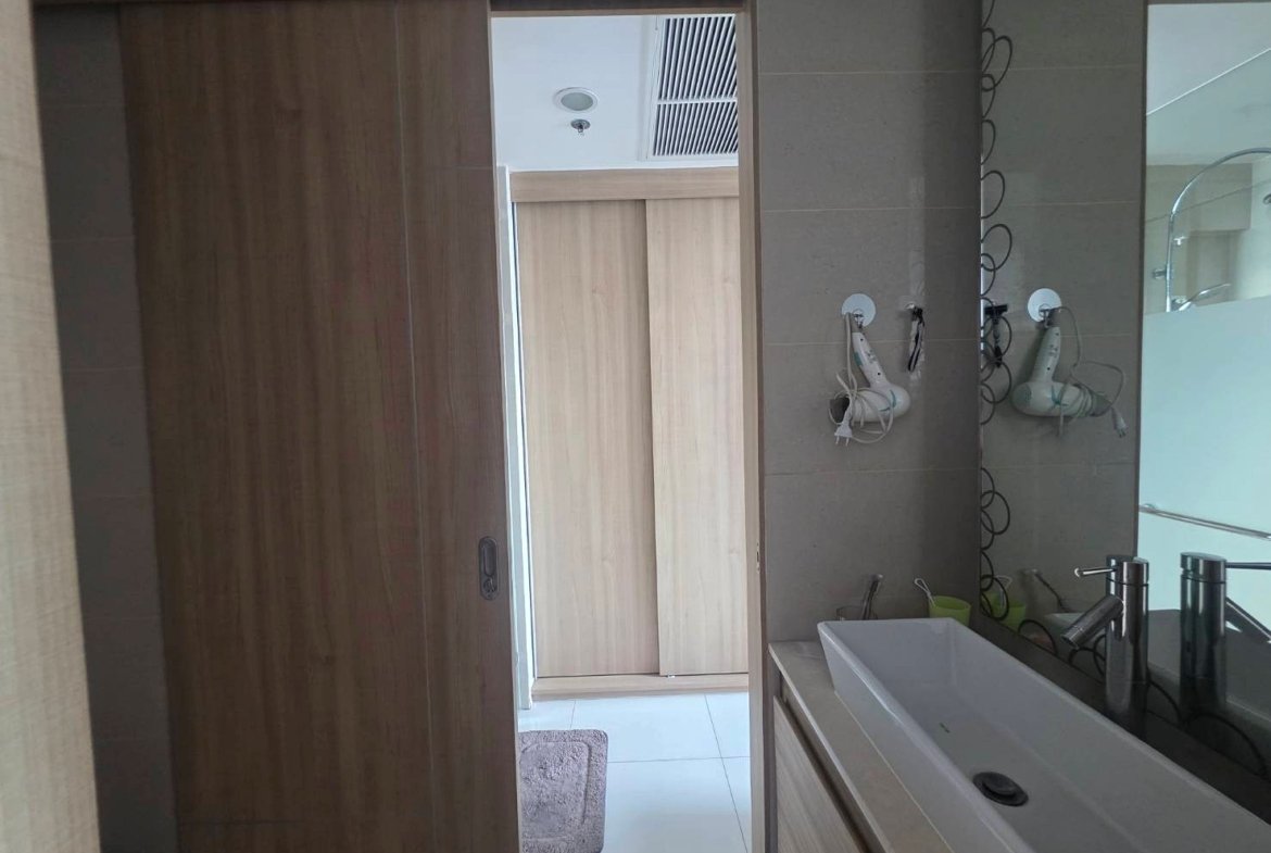 Modern bathroom with white rectangular sink and chrome faucet, wooden vanity/drawers, and a large mirror to the right.