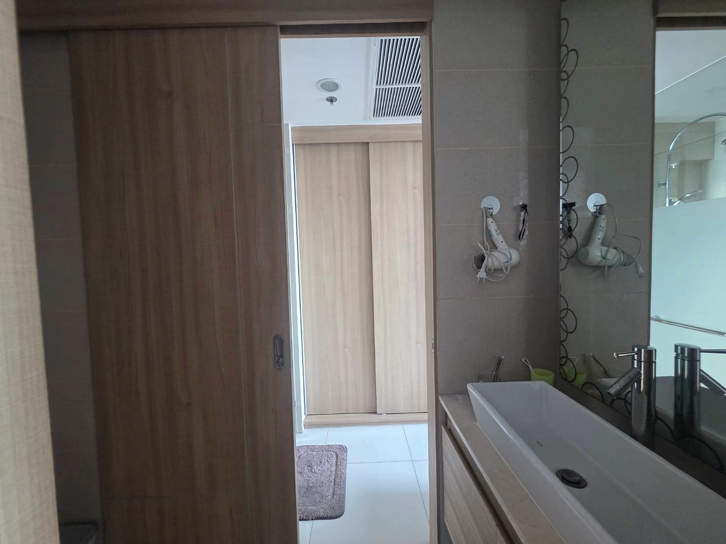 Riviera_Wongamat_B1209_6 Modern bathroom with white rectangular sink and chrome faucet, wooden vanity/drawers, and a large mirror to the right.