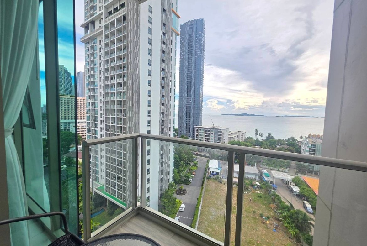 Balcony view of tall white apartment buildings with the sea and distant islands beyond.