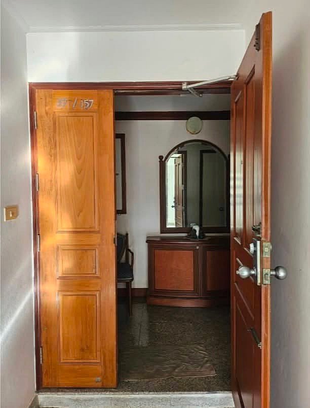 Royal_Cliff_Garden_Pattaya_Dlc639_10 Open wooden doorway revealing a small hallway with a polished wood dresser and round mirror in the back.