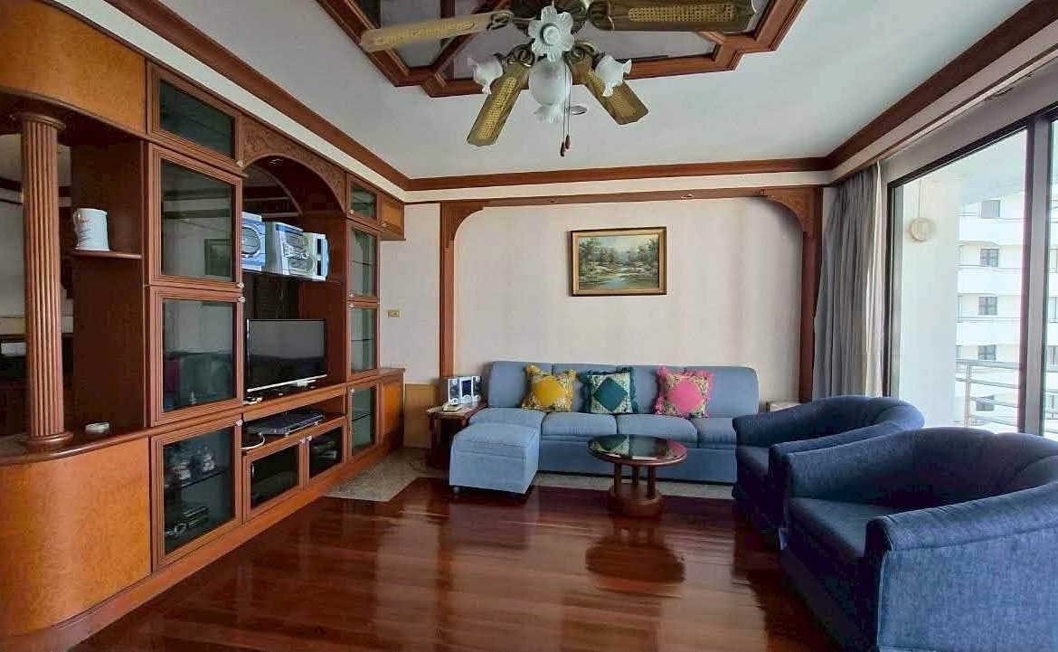 Living room with a blue sectional sofa, two matching chairs, and a wooden wall-unit entertainment center.