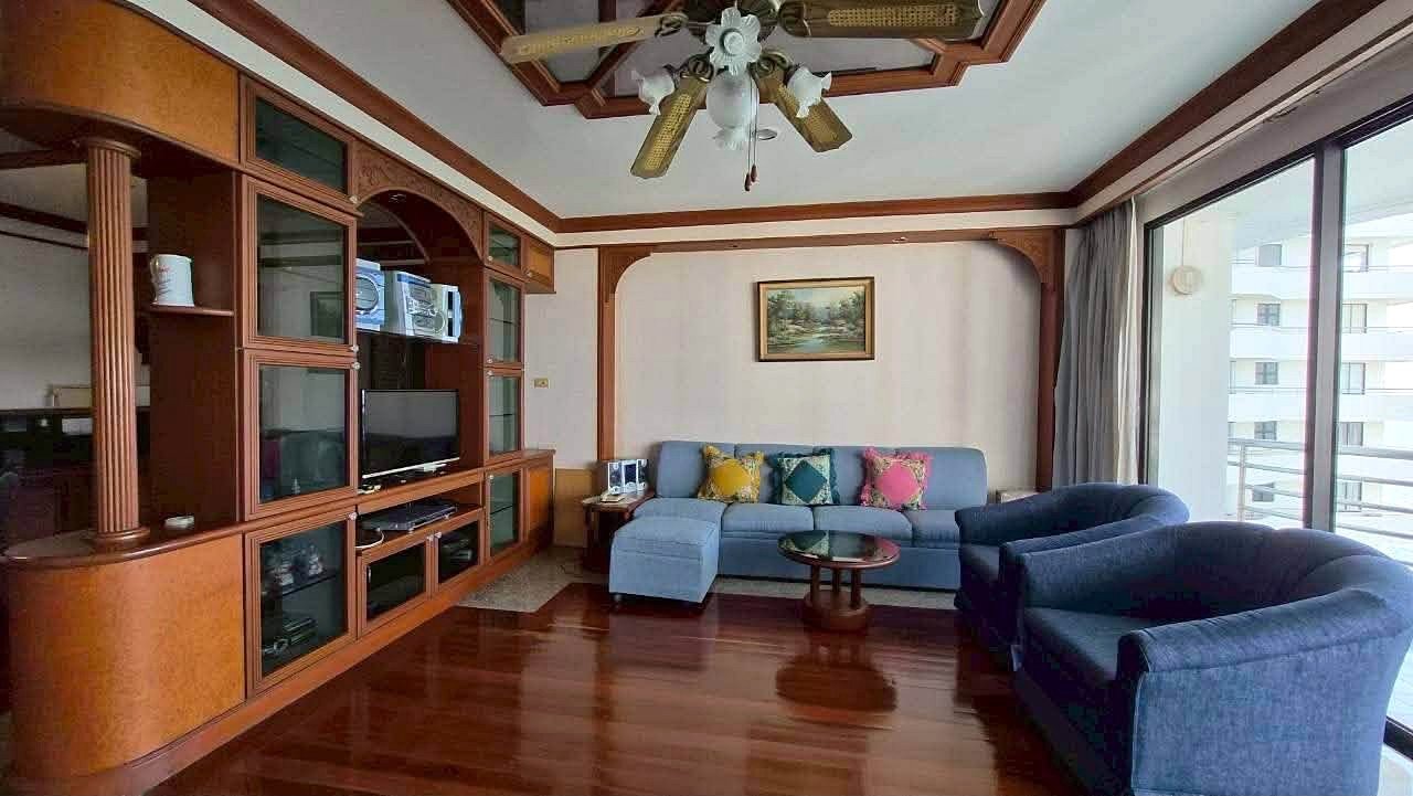 Royal_Cliff_Garden_Pattaya_Dlc639_3 Living room with a blue sectional sofa, two matching chairs, and a wooden wall-unit entertainment center.