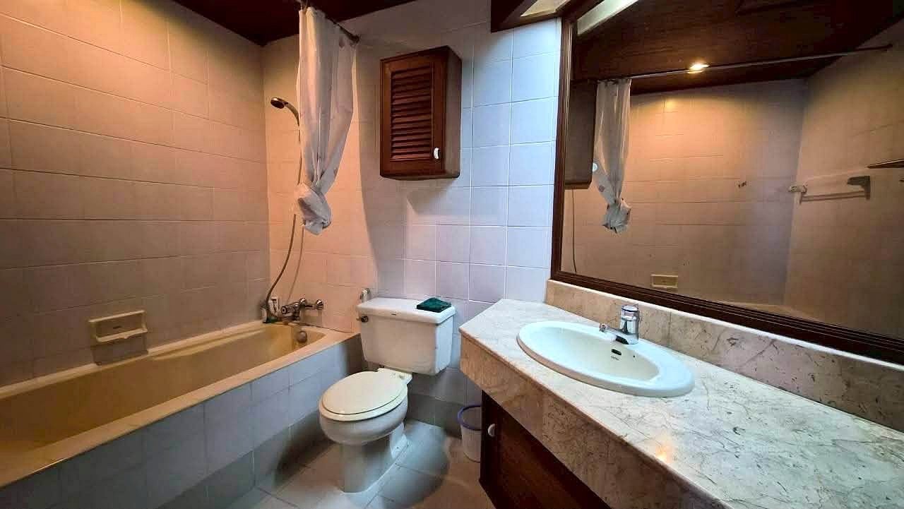 Royal_Cliff_Garden_Pattaya_Dlc639_6 Bathroom with a tub/shower combo, toilet, and marble countertop sink beneath a large mirror with a tied curtain.