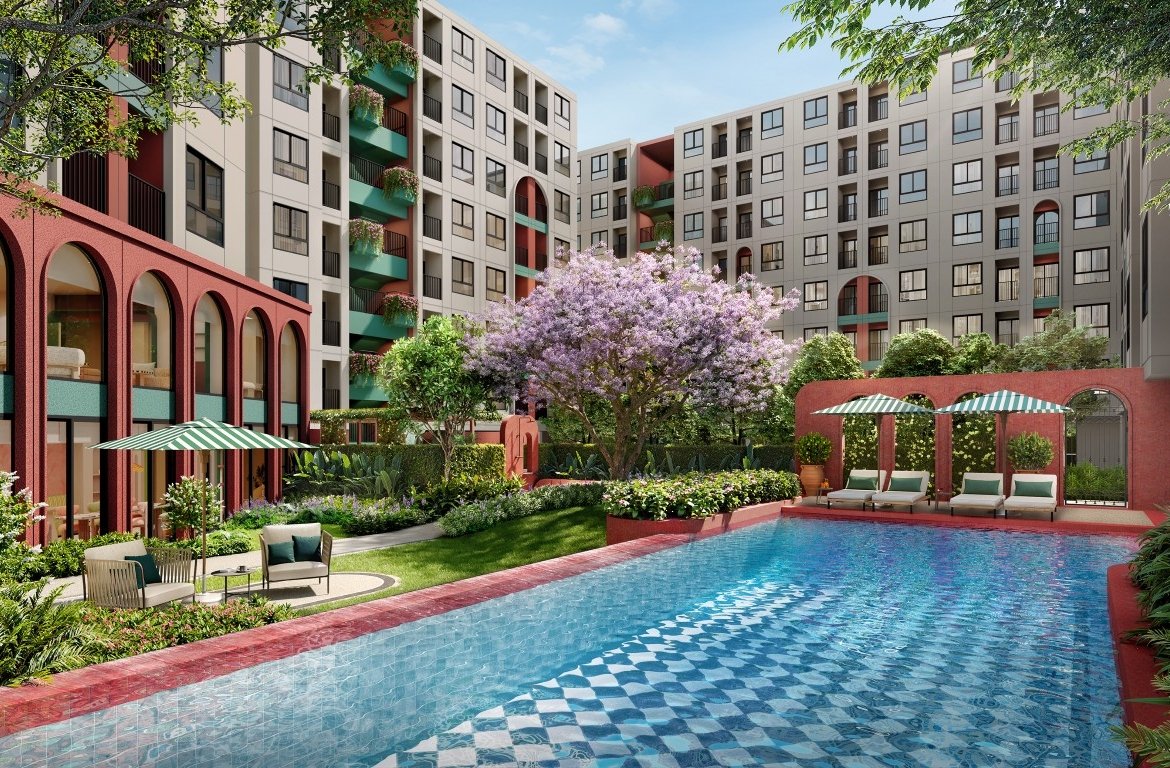 Poolside in a colorful apartment complex: blue tiled pool, striped umbrellas, and lounge chairs set among green landscaping and red arches.