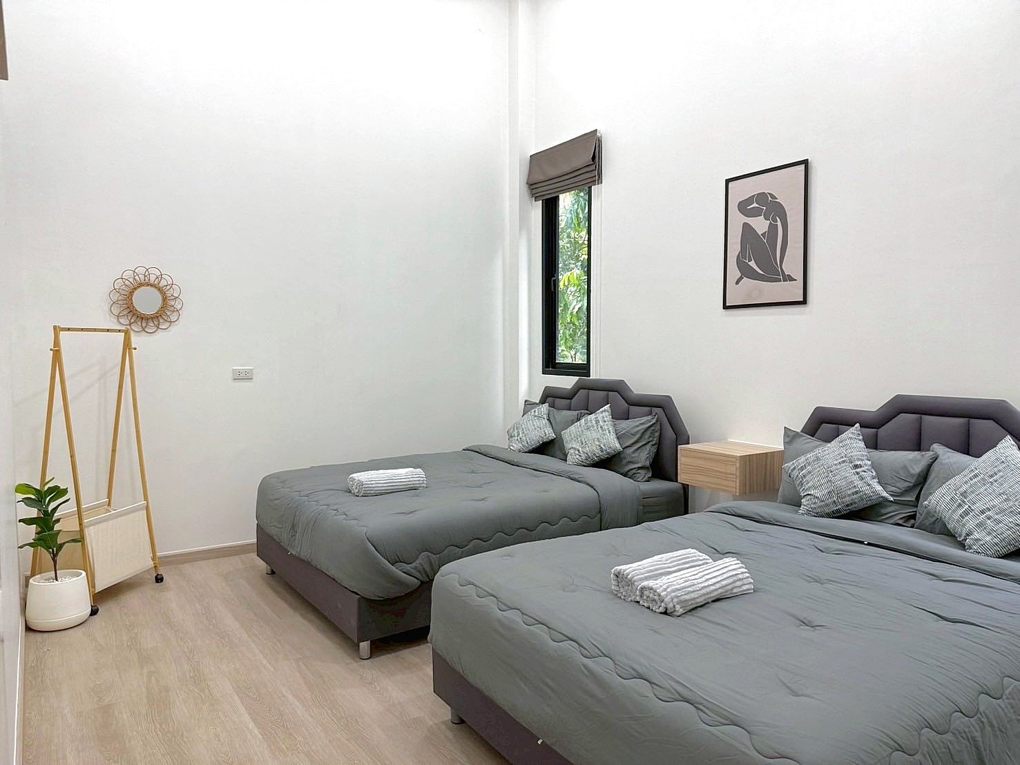 Sunflower_Pool_Villa_7 Twin bedroom with two gray-quilted beds, matching headboards, a wooden nightstand, and a window with a blind; minimalist decor and a potted plant nearby