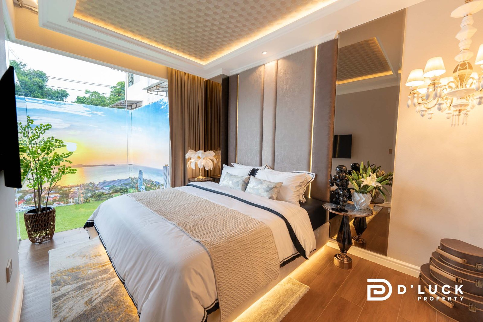 The-Riviera-Malibu-1bedroom 11 Luxurious modern bedroom with a large glass wall showing a sunset cityscape, a king bed with white and beige bedding, and warm ambient lighting.