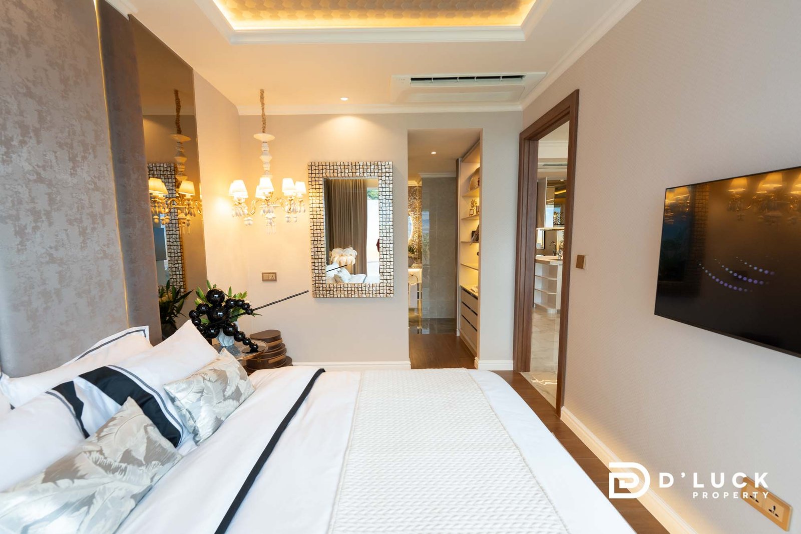 The-Riviera-Malibu-1bedroom 12 Luxurious hotel bedroom with white bedding, decorative pillows, and a chandelier-style light fixture.