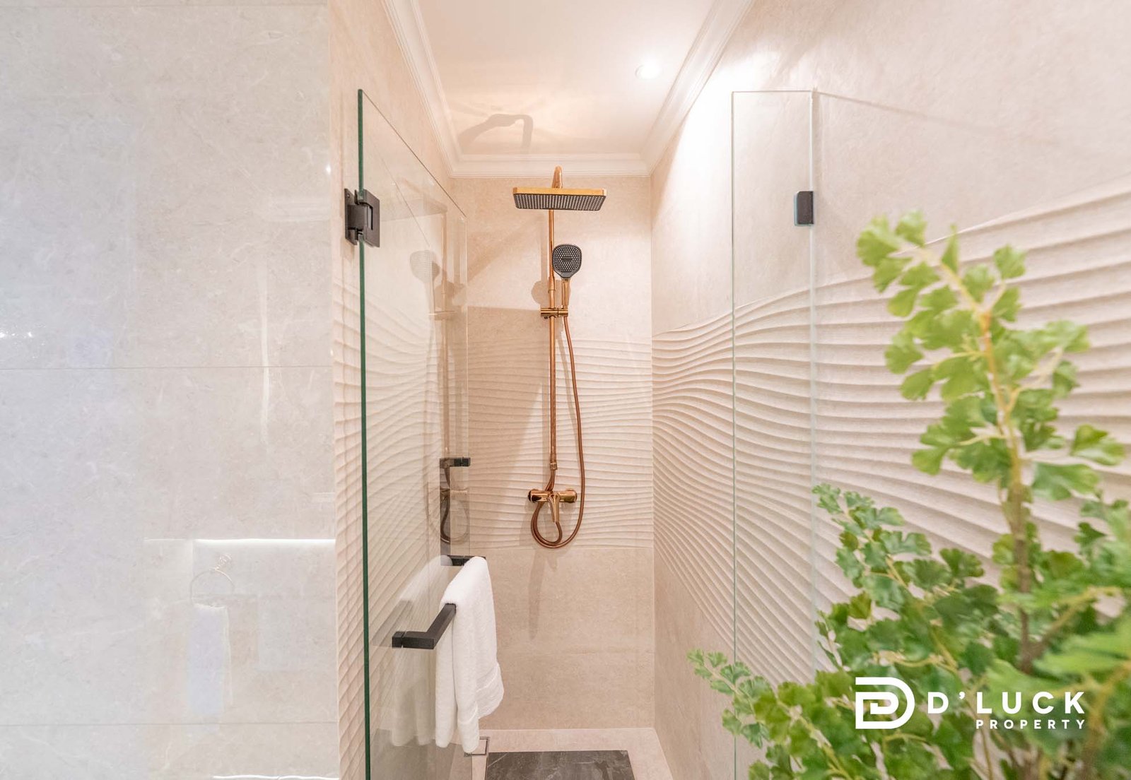 The-Riviera-Malibu-1bedroom 17 Modern glass-walled shower with a square rain showerhead and handheld hose; plant visible on the right.