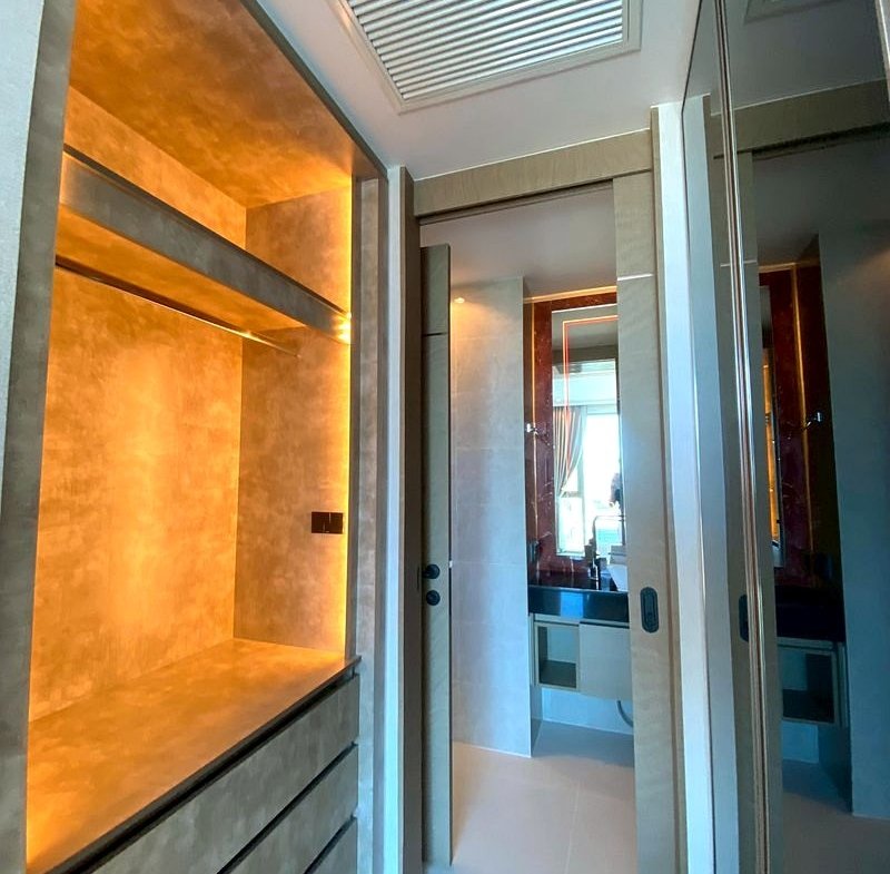 Walk-in closet with warm backlit shelves and gray drawers beneath the lighting glow.