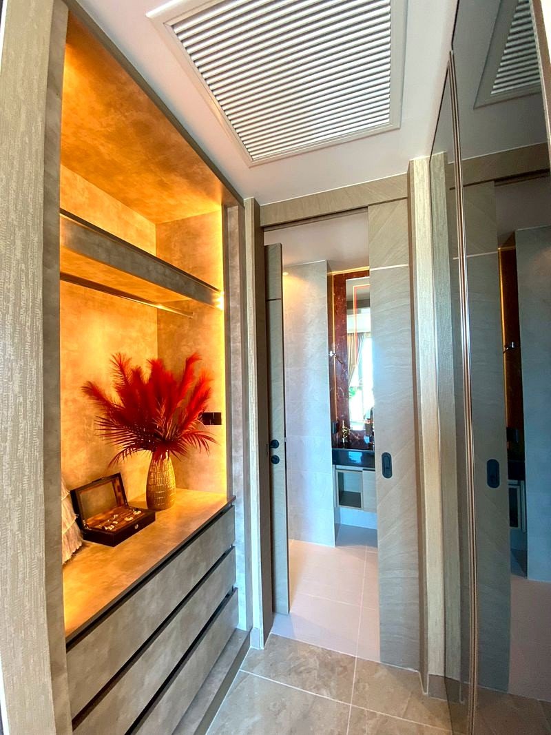 The_Riviera_Ocean_Drive_3914_13 Luxurious hallway with warm amber lighting, a built‑in dresser, and a vase with red dried plumes on the counter.
