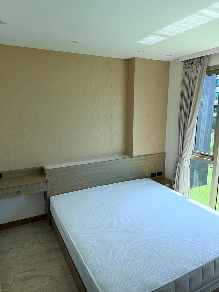 The_Riviera_Ocean_Drive_Dlc628_7 Bedroom in a modern hotel with a white mattress, light wood headboard, and built-in desk under beige wall panels.
