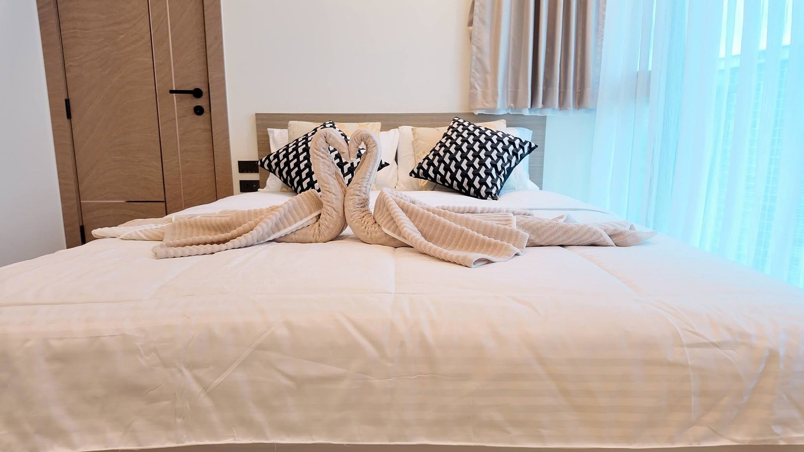 The_Riviera_Ocean_Drive_Pattaya_Dlc601_4 Bed with white bedding and two decorative pillows; beige towels folded into swans form a heart in the center.