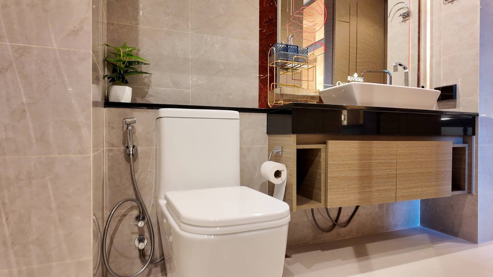The_Riviera_Ocean_Drive_Pattaya_Dlc601_7 Modern bathroom featuring a white toilet, handheld bidet spray, and a dark wood vanity with a white rectangular sink and mirror above.