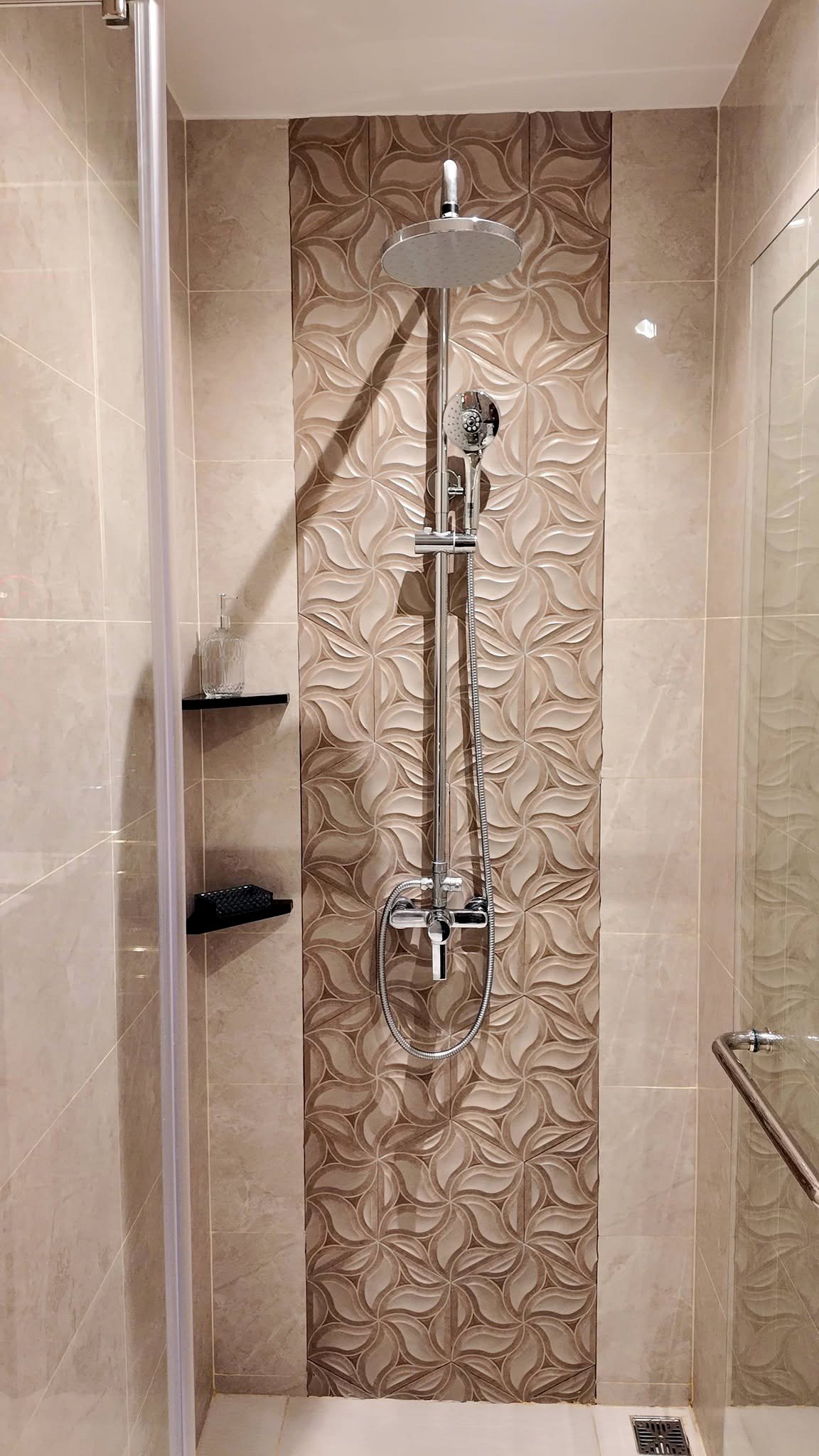 The_Riviera_Ocean_Drive_Pattaya_Dlc601_8 Shower area with a round rainfall showerhead and a handheld spray on chrome fixtures, set against a brown patterned tile stripe.