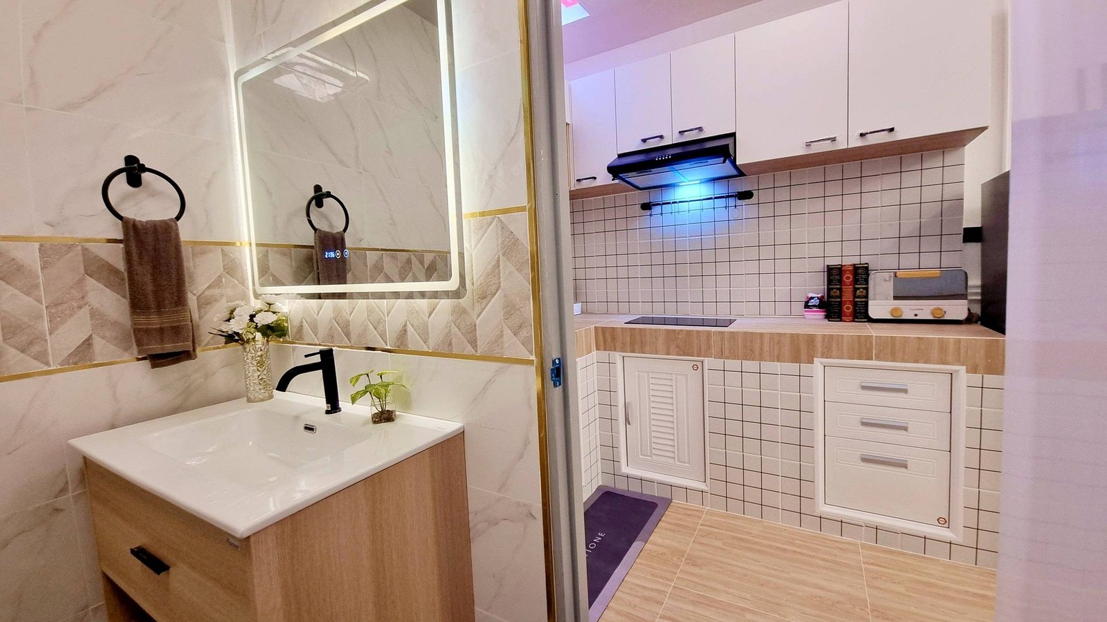 Town_home_Pattaya_Dlh551_16 Modern bathroom vanity with white sink, black faucet, wood cabinet, and circular towel rings; glass partition leads to a tiled kitchen area.