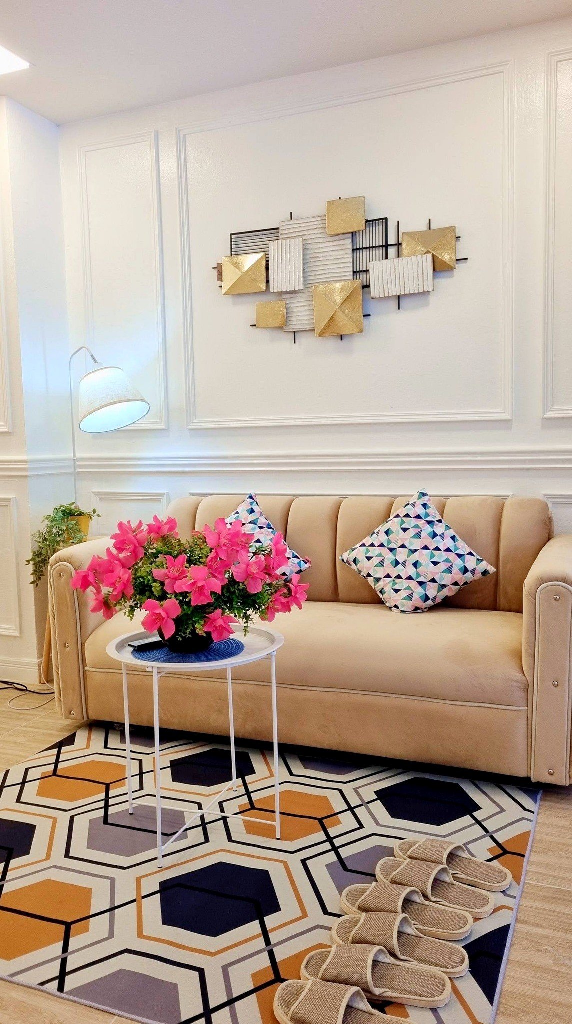 Town_home_Pattaya_Dlh551_3 Beige sofa with geometric-patterned rug, pink flowers on a small table, and modern wall art in a bright living room.