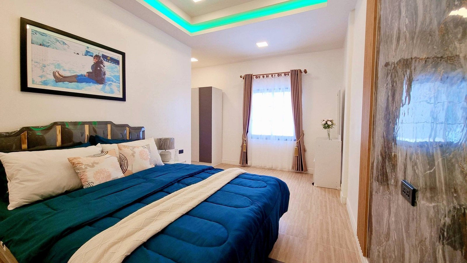 Town_home_Pattaya_Dlh551_5 Bedroom with a large bed covered in a blue comforter and cream quilt, decorative pillows, and a framed photo on the wall