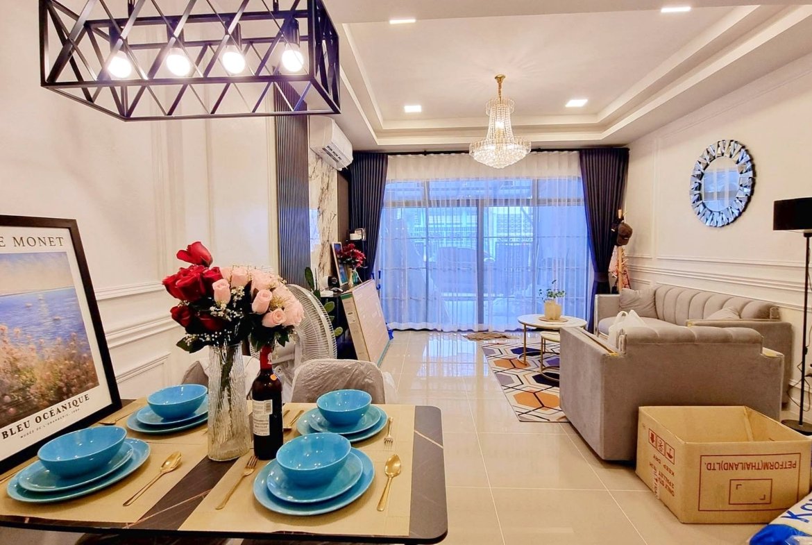 Dining table set with blue bowls and gold cutlery in a bright living room.