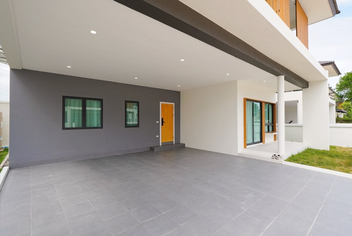 Front of a modern house with a gray accent wall, wooden door, and a large tiled covered patio.
