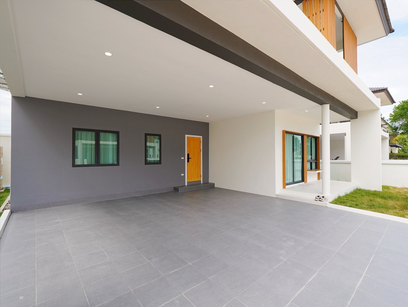 Tropical_Village_3_Pattaya_Dlh453_25 Front of a modern house with a gray accent wall, wooden door, and a large tiled covered patio.