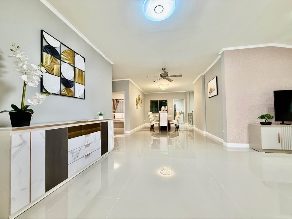Open living and dining area with glossy white tile floors, a marble sideboard, abstract wall art, and a dining table in the background.