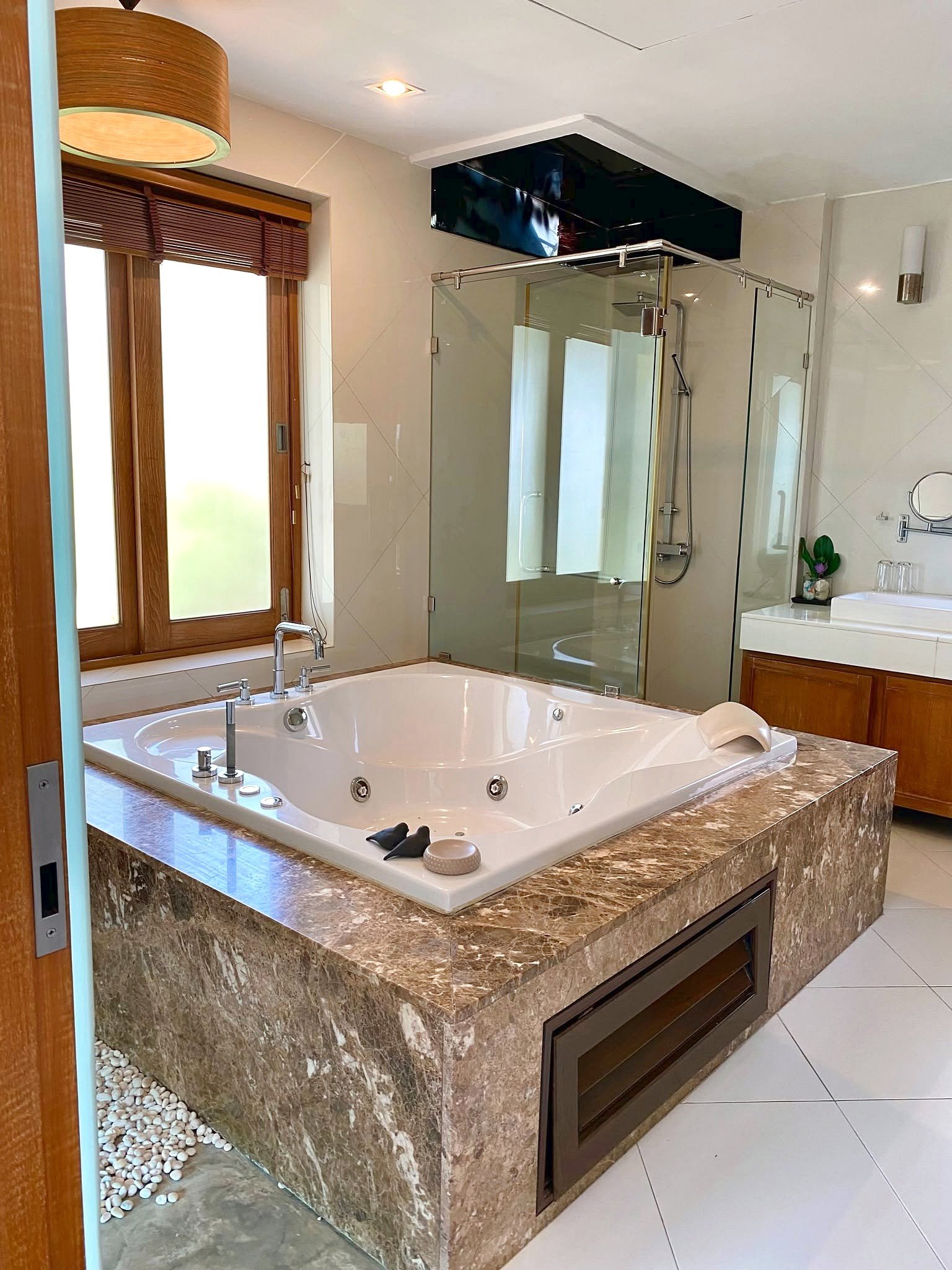 Wongamat_House_Rent_Rdl357_5 Luxurious bathroom with a large oval jacuzzi tub set in a marble surround and a glass-walled shower behind it.