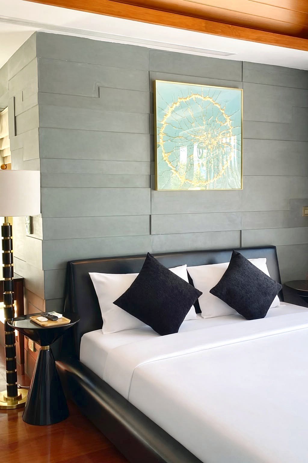 Wongamat_House_Rent_Rdl357_6 Hotel bedroom with a gray paneled accent wall, framed art above a white bed with three black accent pillows.