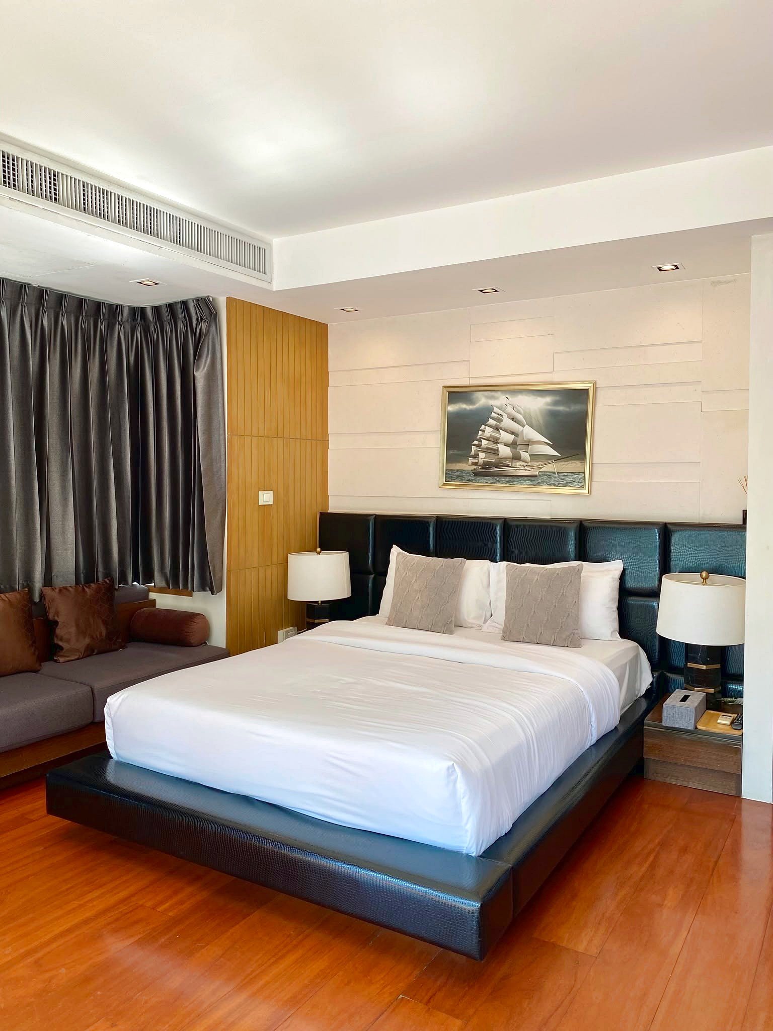 Wongamat_House_Rent_Rdl357_7 Hotel bedroom with a king bed, white linens, dark headboard, and nautical artwork above the bed.