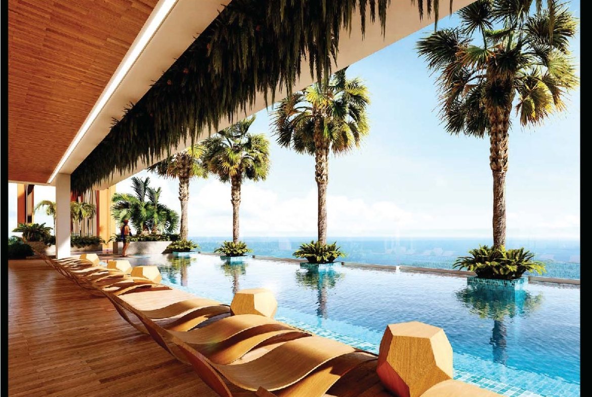 Luxurious outdoor hotel pool area with a wooden deck, curved tan lounge chairs, palm trees, and an ocean view.